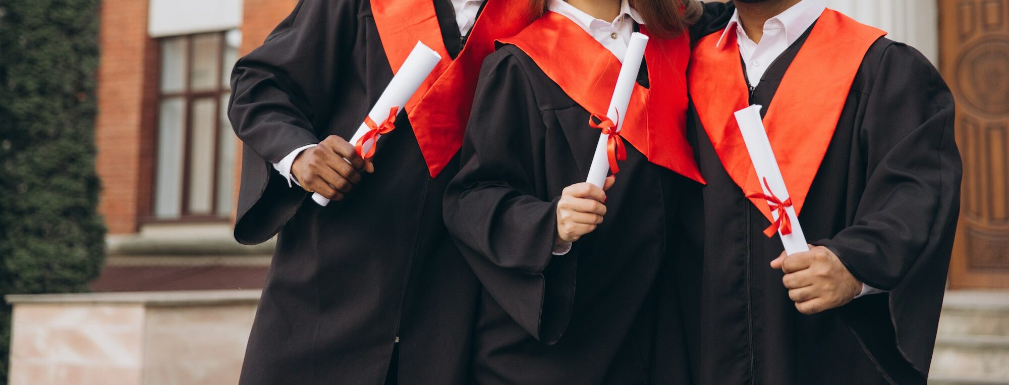 Group of Happy Graduates Celebrating with Diplomas in Hand at University Campus